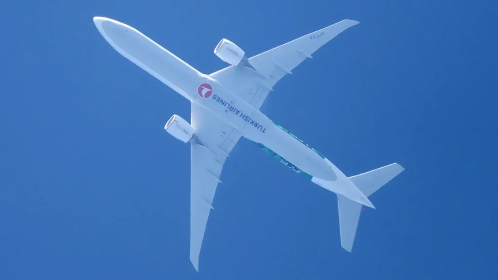 Underside of Turkish Airlines Boeing 777-300ER TC-LJH in flight against blue sky, July 2024 archive photo.