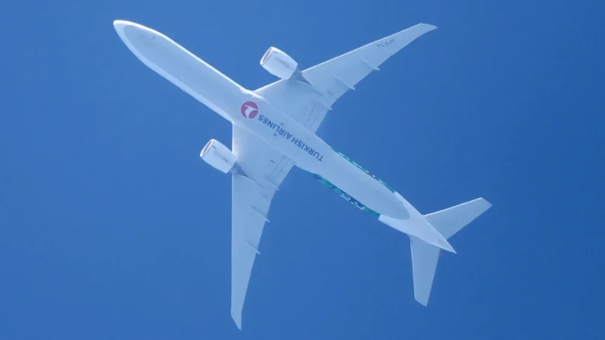 Underside of Turkish Airlines Boeing 777-300ER TC-LJH in flight against blue sky, July 2024 archive photo.