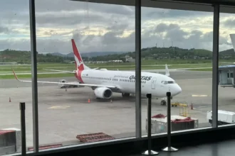 Archive Qantas Boeing 737 at a gate, seen through terminal windows in February 2025; not the Adelaide–Auckland resumption.