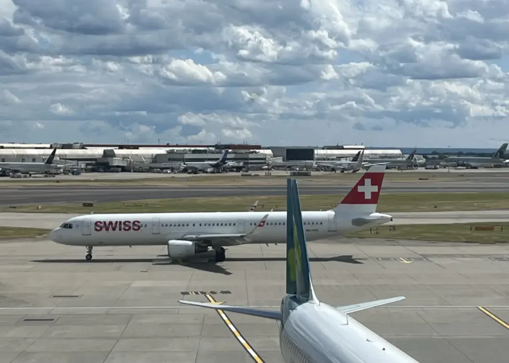 SWISS aircraft taxiing at London Heathrow, with an Aer Lingus tail in the foreground, July 2023.