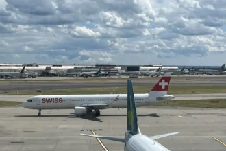 SWISS aircraft taxiing at London Heathrow, with an Aer Lingus tail in the foreground, July 2023.