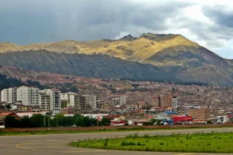 Archive view of Cusco airport pavement, city buildings and surrounding mountains in November 2018.
